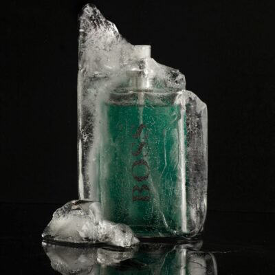 Elegant product shot of a perfume bottle encased in ice, highlighting luxury on a black background.