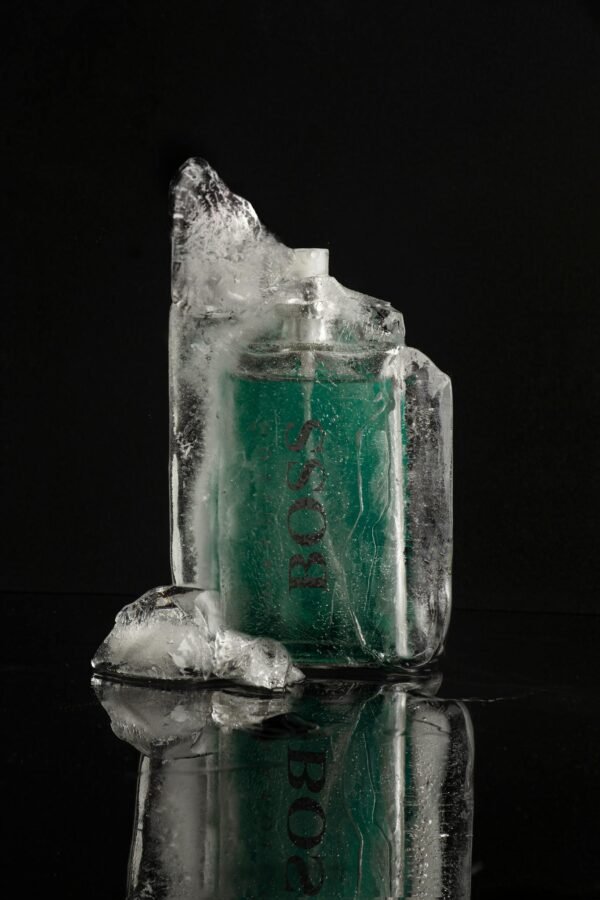 Elegant product shot of a perfume bottle encased in ice, highlighting luxury on a black background.
