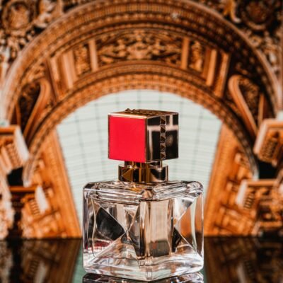 Luxurious perfume bottle against ornate backdrop on reflective surface, showcasing elegance and style.