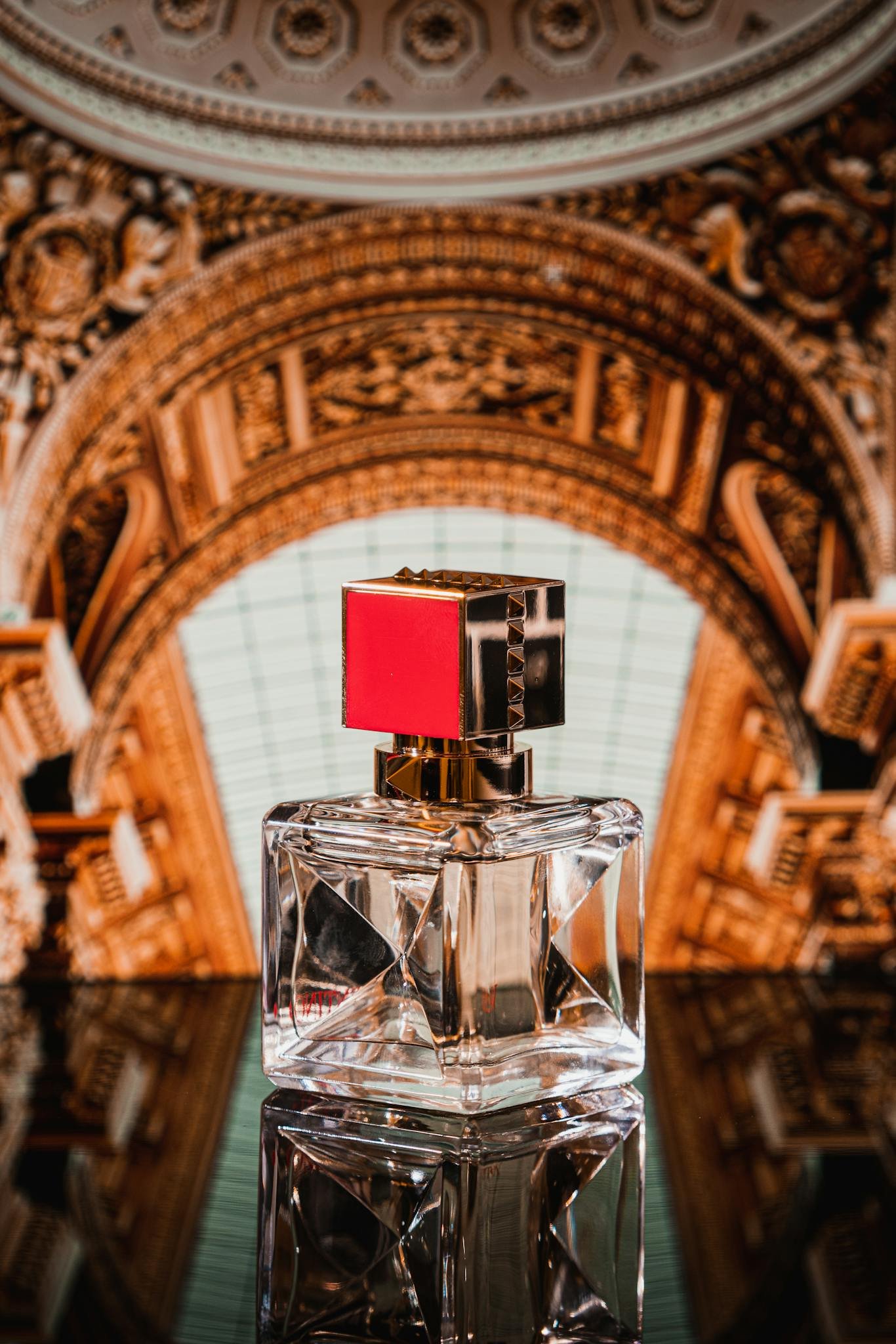 Luxurious perfume bottle against ornate backdrop on reflective surface, showcasing elegance and style.