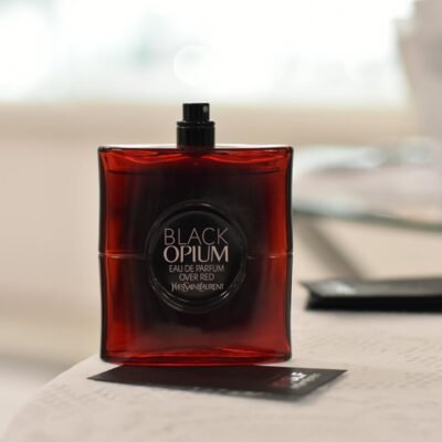 Red luxury perfume bottle on a table with blurred background, exuding elegance and style.