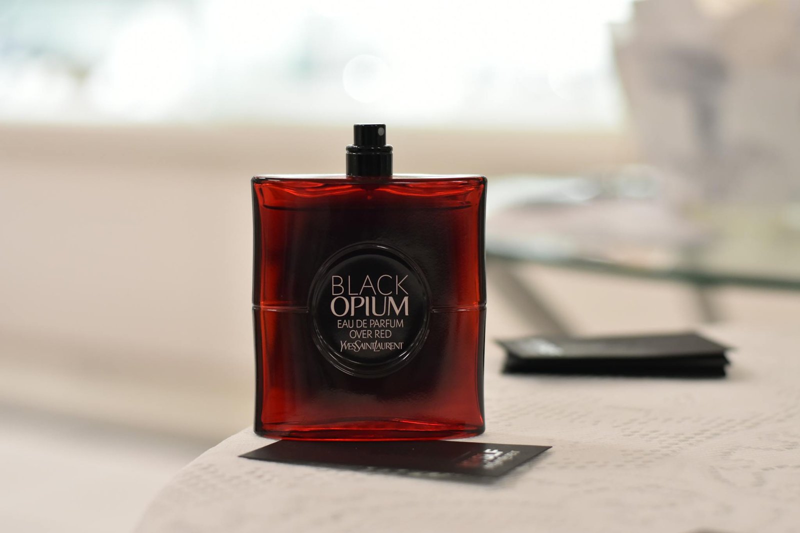Red luxury perfume bottle on a table with blurred background, exuding elegance and style.